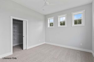Empty bedroom at 136 Elm Street with three windows, light gray walls, beige carpet, and an open closet with shelves.