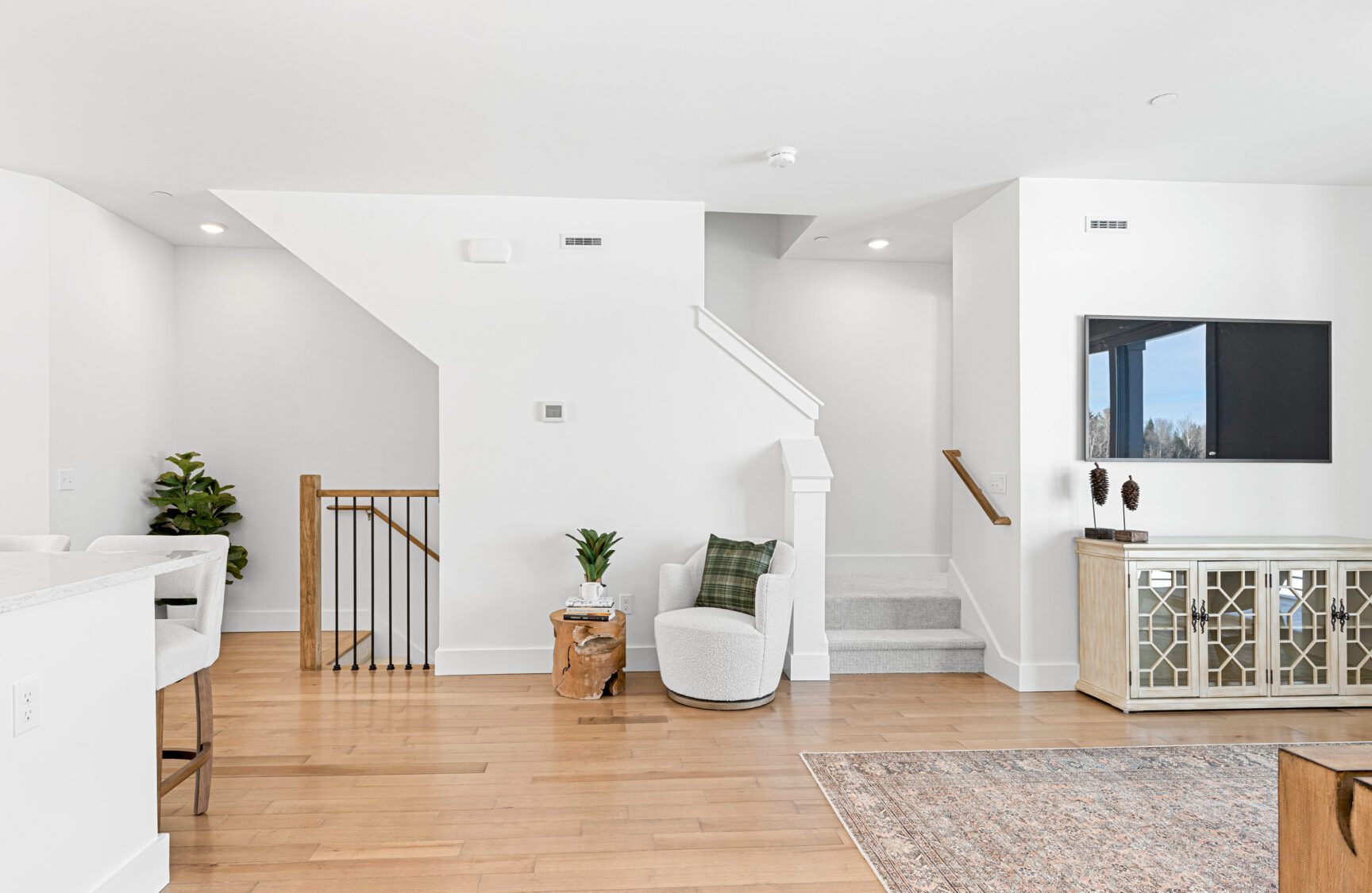 Modern living room at 196 Alpine Drive with light wood floors, white walls, stairway, and minimalistic furniture.