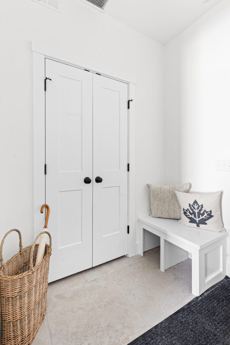 Welcome to 196 Alpine Drive: white double doors, cozy bench, and wicker basket in a bright modern entryway.