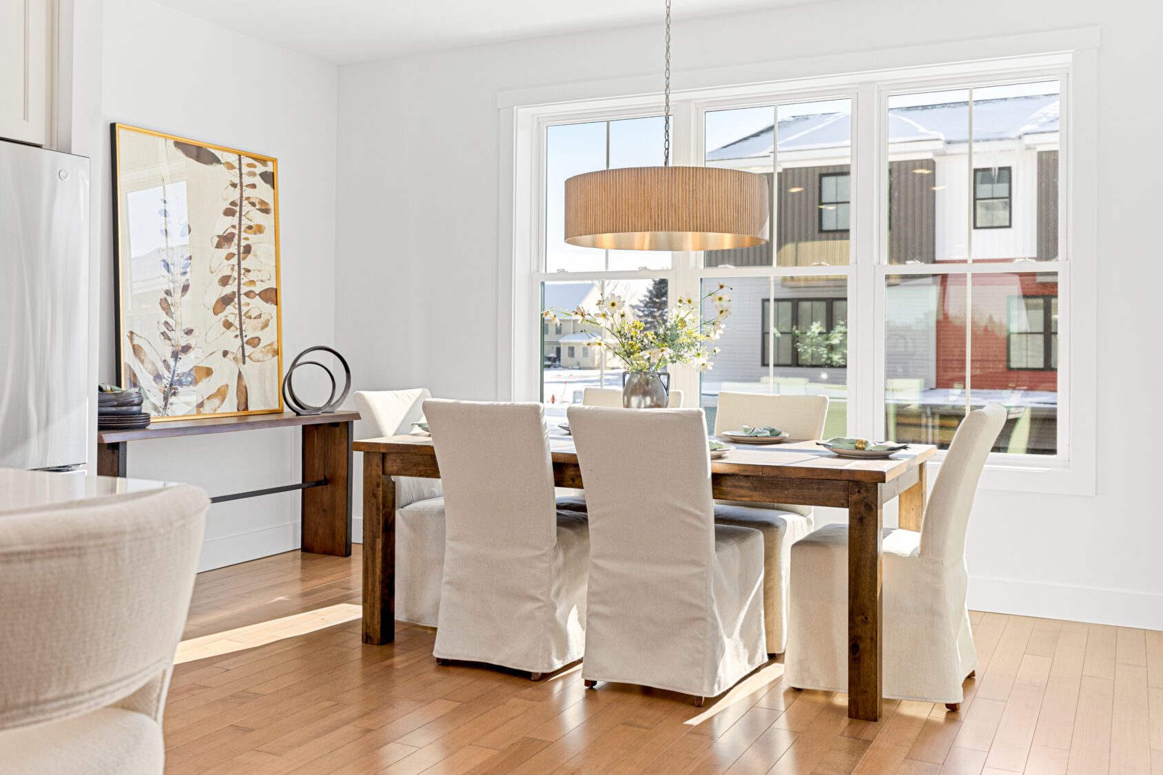 Bright dining room at 196 Alpine Drive with a wooden table, six white chairs, large window, and modern decor.