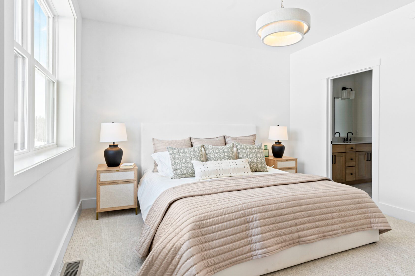 Bright, modern bedroom at 196 Alpine Drive with neatly made bed, side tables, lamps, and open door to the bathroom.