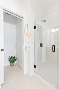 Minimalist bathroom at 196 Alpine Drive with a glass shower, white towel on a hook, and a potted plant in the corner.