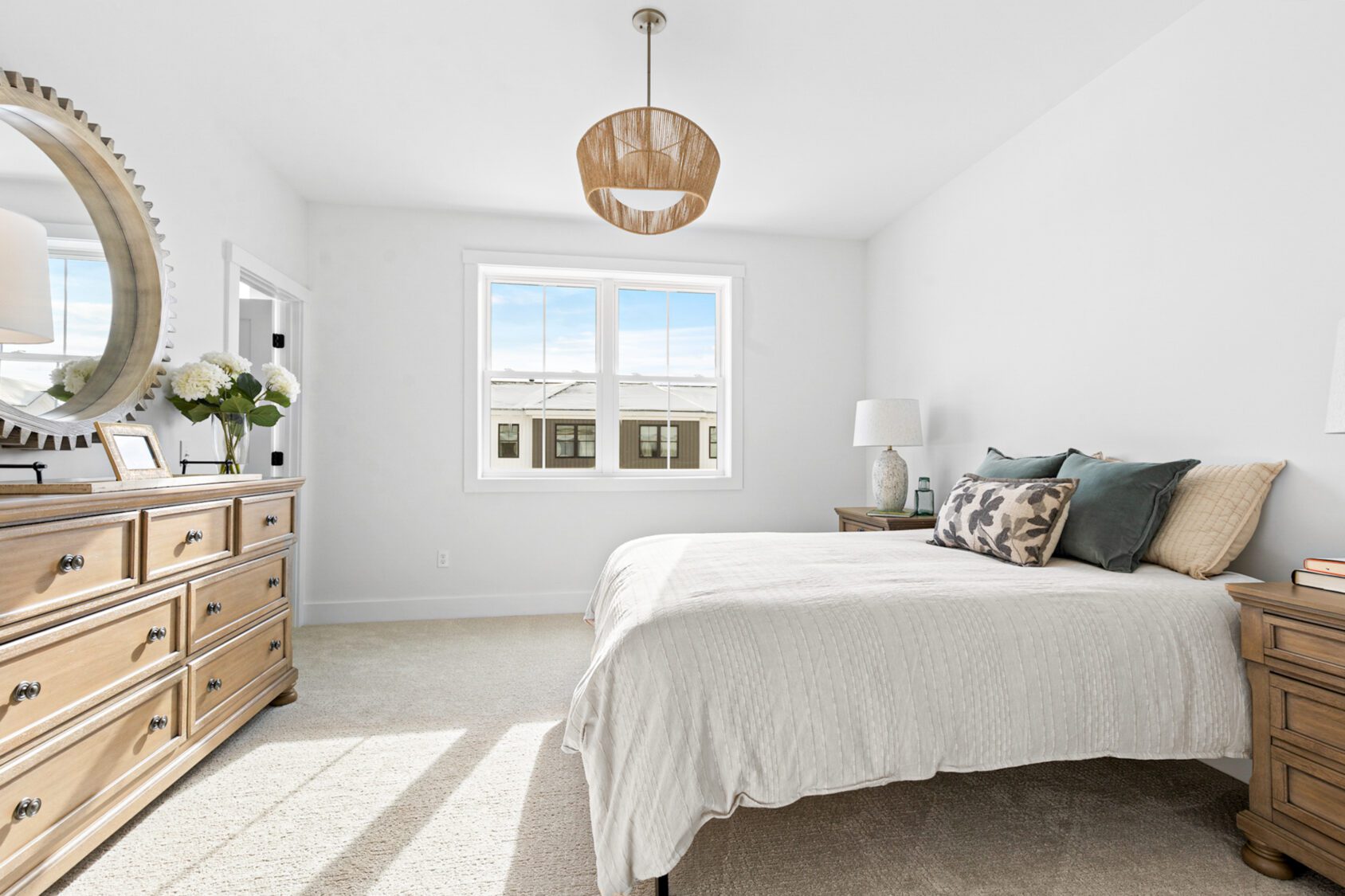 Bright bedroom at 196 Alpine Drive with a neatly made bed, wooden furniture, round mirror, and natural light.