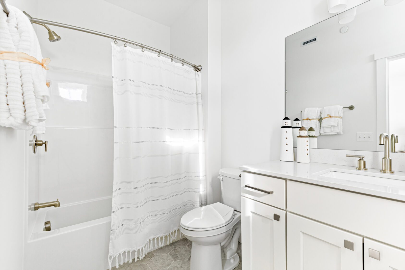 Bright white bathroom at 196 Alpine Drive with shower, vanity, large mirror, and nautical-themed decor.