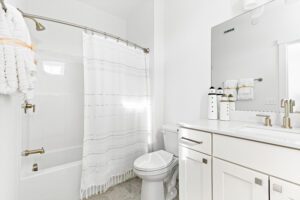 Bright white bathroom at 196 Alpine Drive with shower, vanity, large mirror, and nautical-themed decor.
