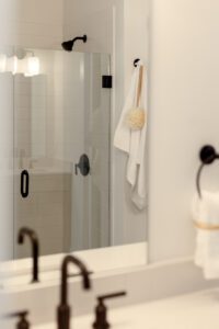 Modern bathroom at 196 Alpine Drive with glass shower, white towel, bath sponge on wall hook, and sleek black fixtures.