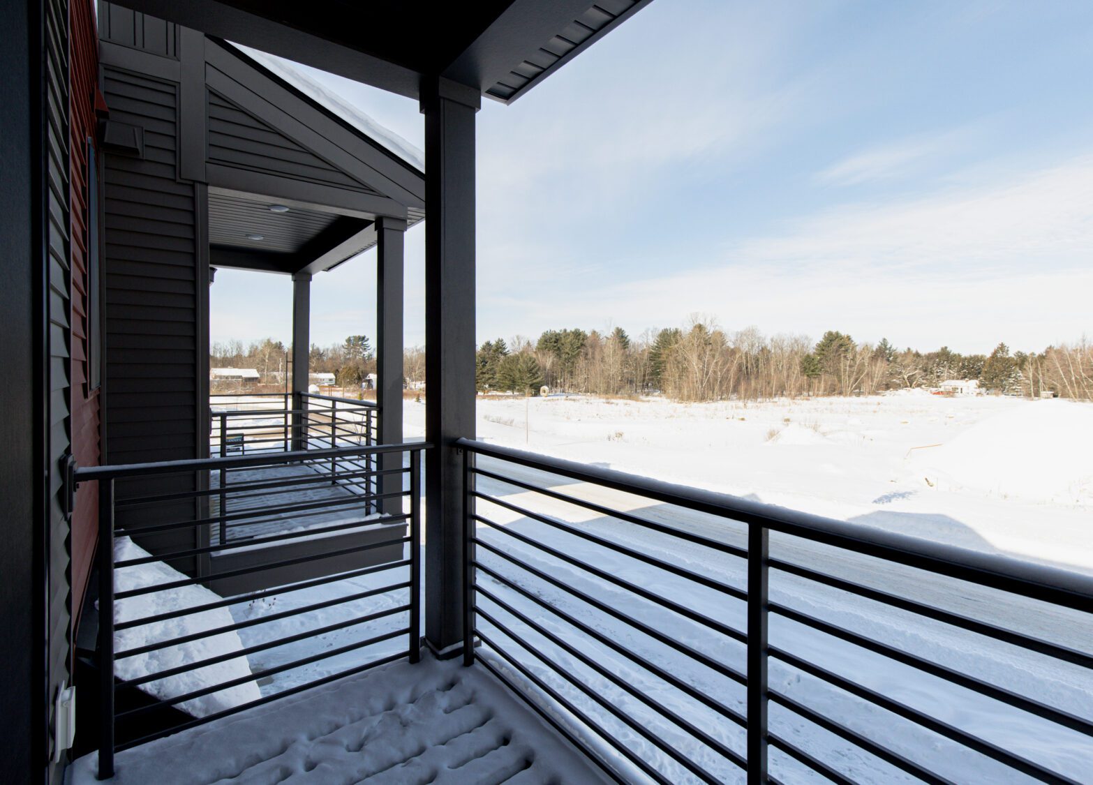 Snow-covered balcony at 196 Alpine Drive overlooks a snowy landscape and trees under a partly cloudy sky.