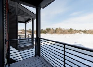 Snow-covered balcony at 196 Alpine Drive overlooks a snowy landscape and trees under a partly cloudy sky.