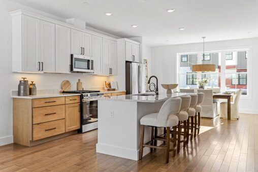 Bright modern kitchen at 196 Alpine Drive with white cabinets, wood accents, island seating, and dining area by large windows.