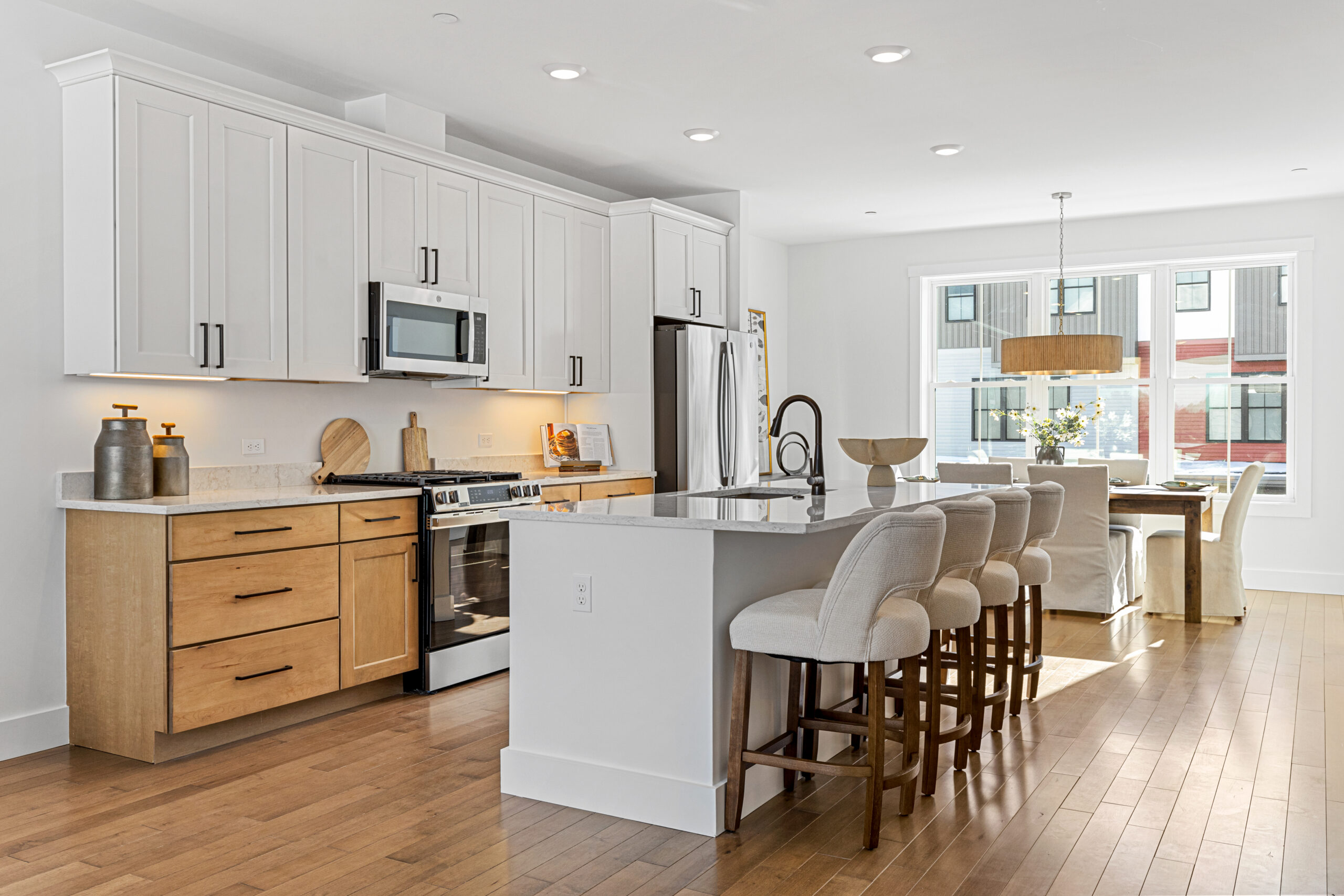 Bright modern kitchen at 196 Alpine Drive with white cabinets, wood accents, island seating, and dining area by large windows.
