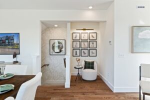 A cozy nook at 162 Alpine Drive with a round chair, wall art, and a small table beside a staircase in a bright, modern home.