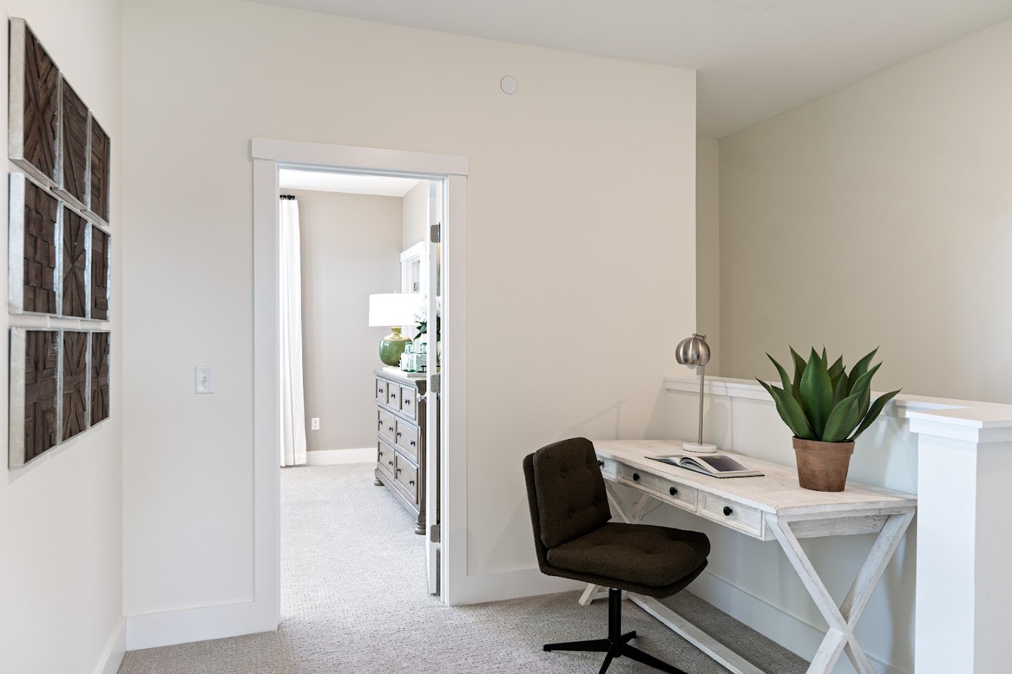 Small home office at 162 Alpine Drive with a white desk, dark chair, plant, and wall art by an open doorway to the bedroom.