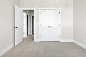 Empty beige Castlerock Paired Villa room with white double closet doors, an open door, and light carpeted floor.